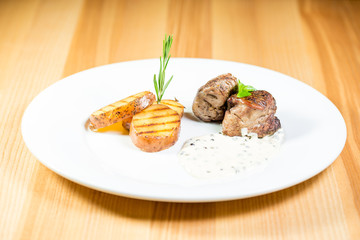Beautiful juicy grilled meat with fried potatoes on a wooden table