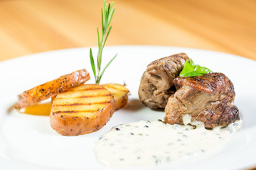 Beautiful juicy grilled meat with fried potatoes on a wooden table