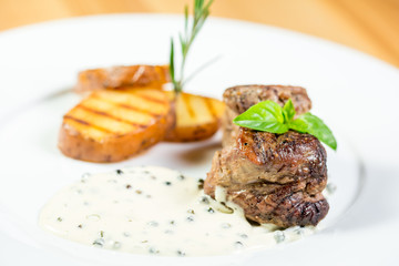 Beautiful juicy grilled meat with fried potatoes on a wooden table