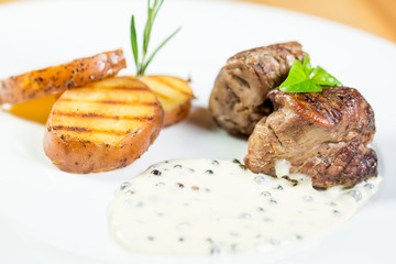 Beautiful juicy grilled meat with fried potatoes on a wooden table