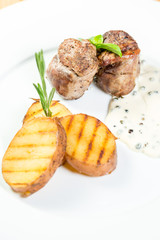 Beautiful juicy grilled meat with fried potatoes on a wooden table