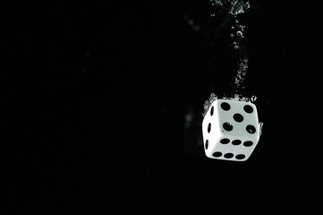 Dice falling into water. On a black background.