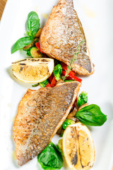 Tasty baked fish with grilled vegetables on  plate on wooden table close-up