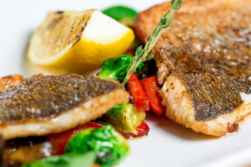 Tasty baked fish with grilled vegetables on  plate on wooden table close-up