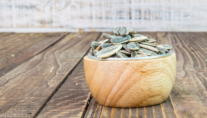 Sunflower seeds in a cup on a wooden background.
