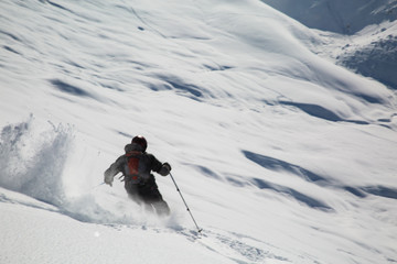 Male skier skiing in fresh snow on ski slope on a sunny winter day at the ski resort in Georgia