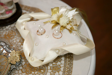 gold rings for wedding are on decorative pillow