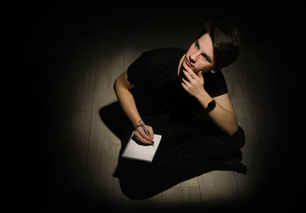 Teenager young man thinking and writing on notebook on black bac