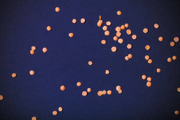 Orange lentils scattered on the black background. Toned