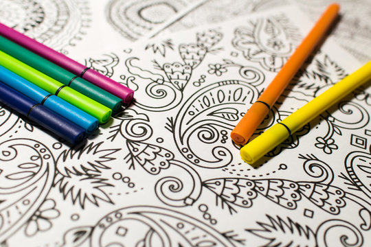 Trend für Stressabbau - Ausmalbuch für Erwachsene - Stifte in verschiedenen Farben auf einem Blatt Papier mit Muster zum Ausmalen . Nahaufnahme