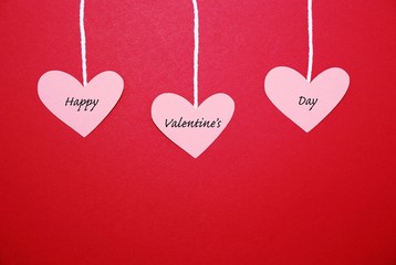 Hearts hanging from string on a red background with the text Happy Valentine's Day