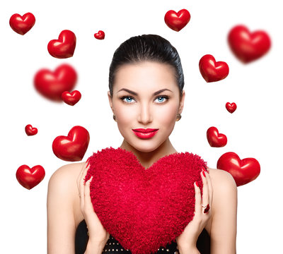 Gorgeous young brunette woman with heart shaped red pillow. Perfect make up. Valentine' Day
