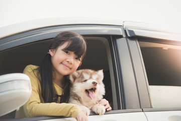 asian girl and siberian husky puppy sitting in the car