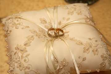gold wedding rings lie on a decorative pillow