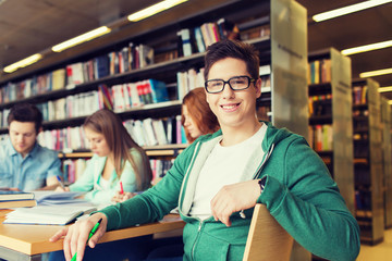 Obraz premium happy student boy reading books in library