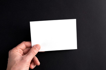 Men's hands holding a white blank sheet of paper