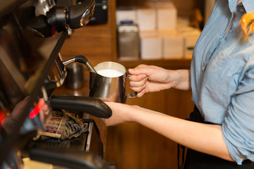 close up of woman making coffee by machine at cafe