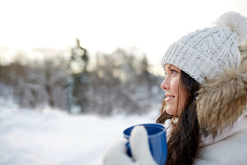 happy young woman with tea cup outdoors in winter