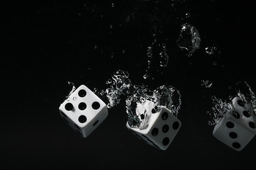 Dice falling into water. On a black background.
