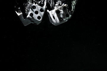 Dice falling into water. On a black background.