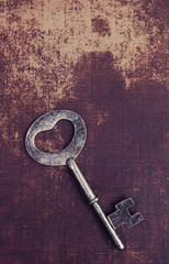 Old vintage key on a faux leather material surface