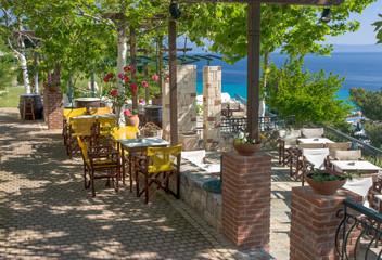 Fototapeta na wymiar Shaded greek cafe terrace overlooking the sea gulf