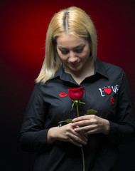 beautiful young woman with red rose on dark background