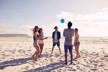 Young people playing with ball at the beach