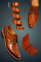 Brown man shoes,belt and wallet against blue background,