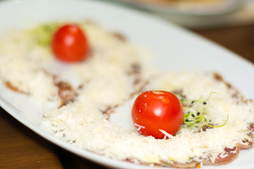 Appetizer carpaccio with Parmesan cheese, cherry tomatoes and sprouts.