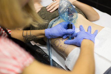 Tattooing artist. Process of a woman making a tattoo