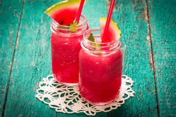 Fresh watermelon smoothie drink in mason jar on black stone.