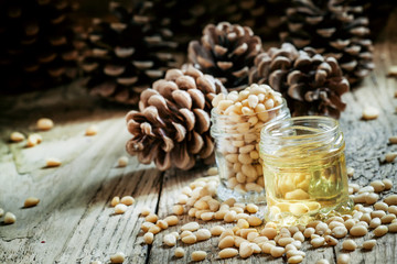 Cedar oil and cedar nuts on an old wooden background with cones,