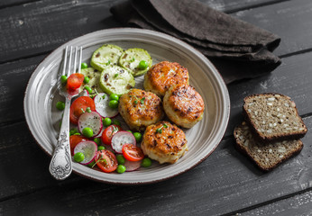 Chicken cutlets and fresh vegetable salad on ceramic plate on dark wooden background. Healthy and tasty food