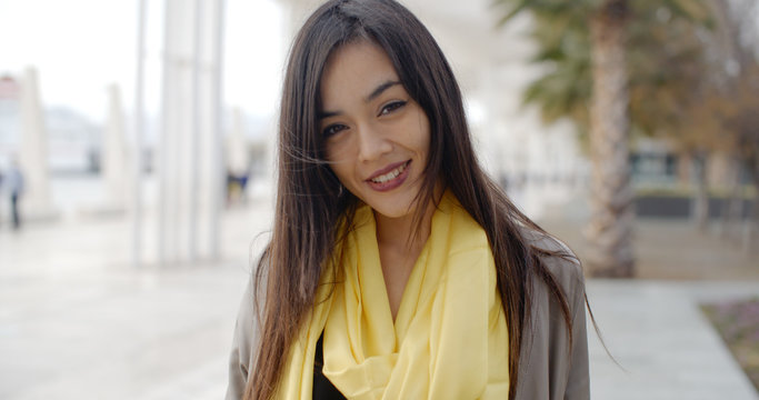 Single joyful grinning woman in yellow scarf standing outdoors need palm trees and buildings