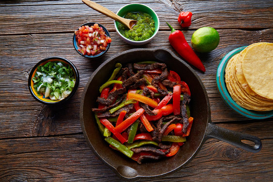 Beef fajitas in a pan with sauces Mexican food