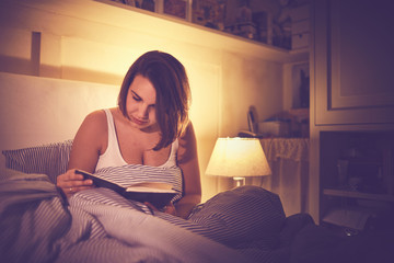 giovane ragazza legge libro a letto