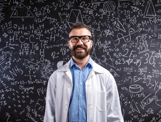 Teacher in white coat  and eyeglasses against big blackboard wit