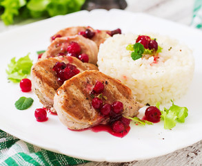 Pork medallions steak with cranberry sauce and a side dish of rice