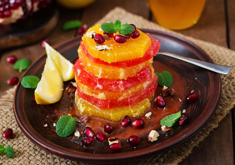 Fruit salad with grapefruit and orange, pomegranate seeds, honey and lemon, decorated with mint