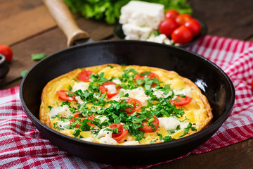 Omelet with tomatoes, parsley and feta cheese in pan