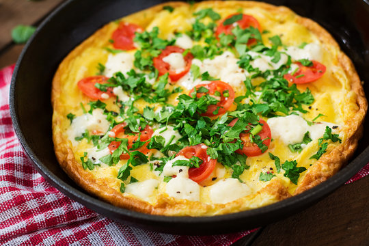 Omelet with tomatoes, parsley and feta cheese in pan