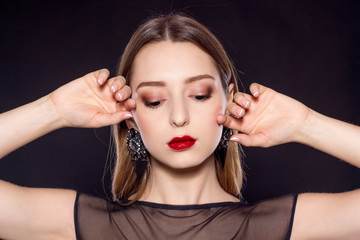 Portrait of a beautiful young woman on a black background. Beautiful woman with red lips in black dress.