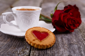 Valentines Day card - Cookies with heart and cup of coffee, red rose at old wooden background