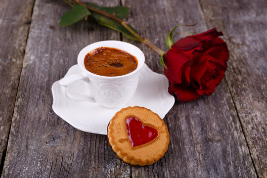 Valentines Day card - Cookies with heart and cup of coffee, red rose at old wooden background