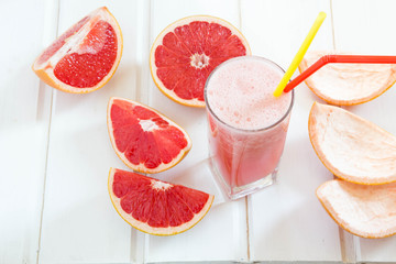 Grapefruit juice and ripe grapefruits on a wooden background