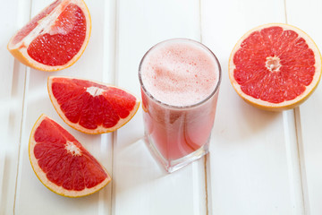 Grapefruit juice and ripe grapefruits on a wooden background