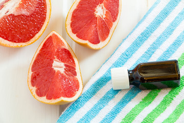 Essential oil in glass bottle with fresh, juicy grapefruit. Spa concept.