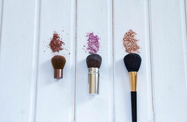 women's accessories cosmetics. Makeup brushes and crushed eyeshadow on wooden background