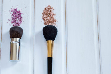 women's accessories cosmetics. Makeup brushes and crushed eyeshadow on wooden background